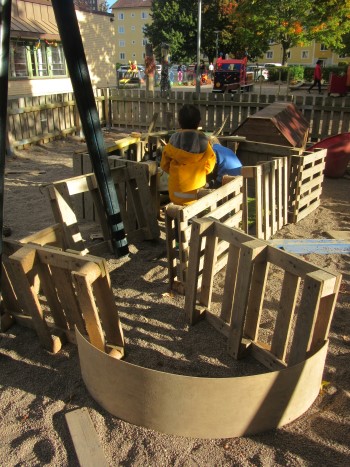 Ett barn har byggt med lastpallar och träbitar och gjort ett hus ute på förskolegården